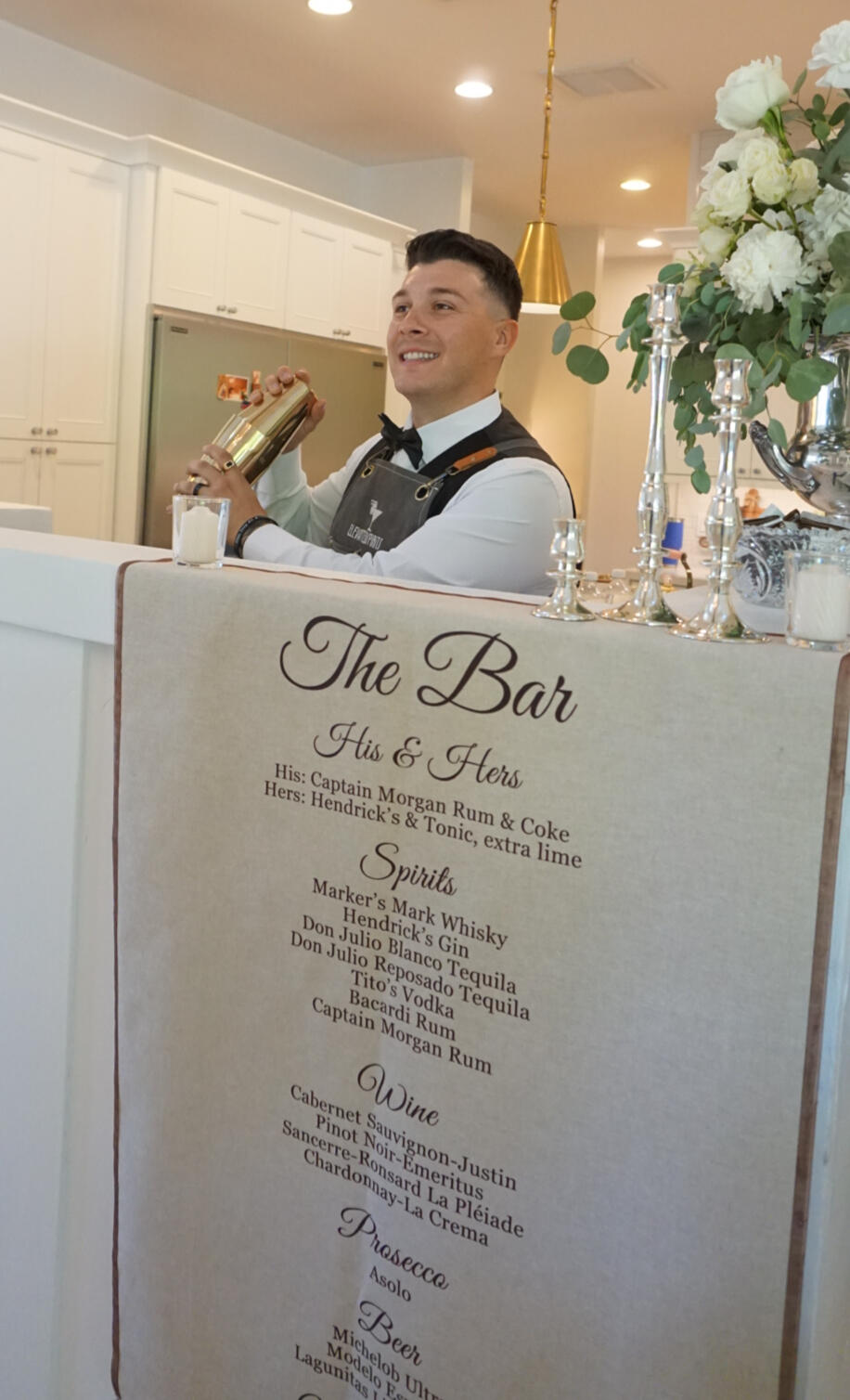 Wedding Bartending Service Elevated Spirits bartender preparing drinks behind a decorated wedding bar.
