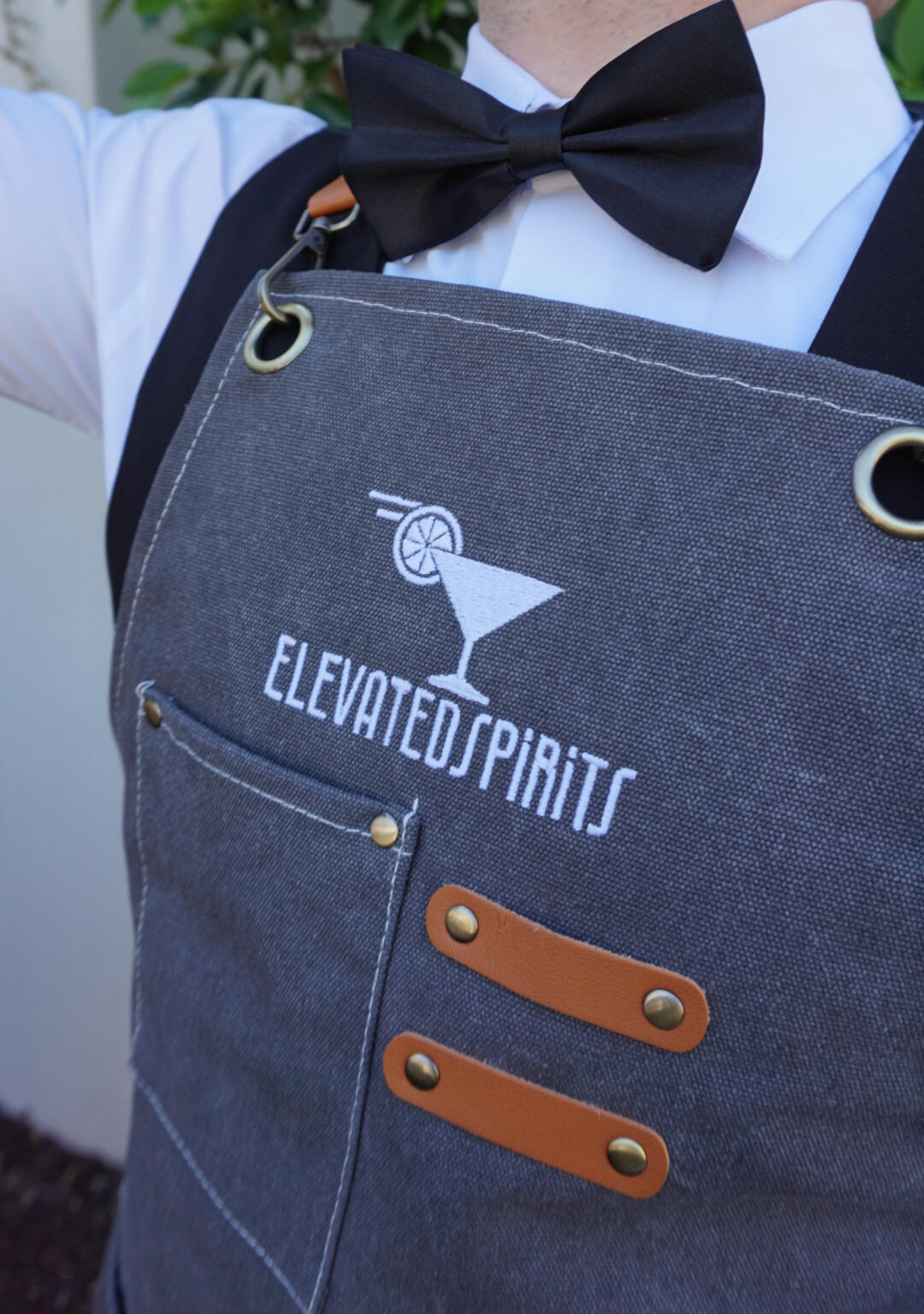 Elevated Spirits Bartender Uniform Close-up of an Elevated Spirits branded bartender apron, white shirt, and black bow tie.