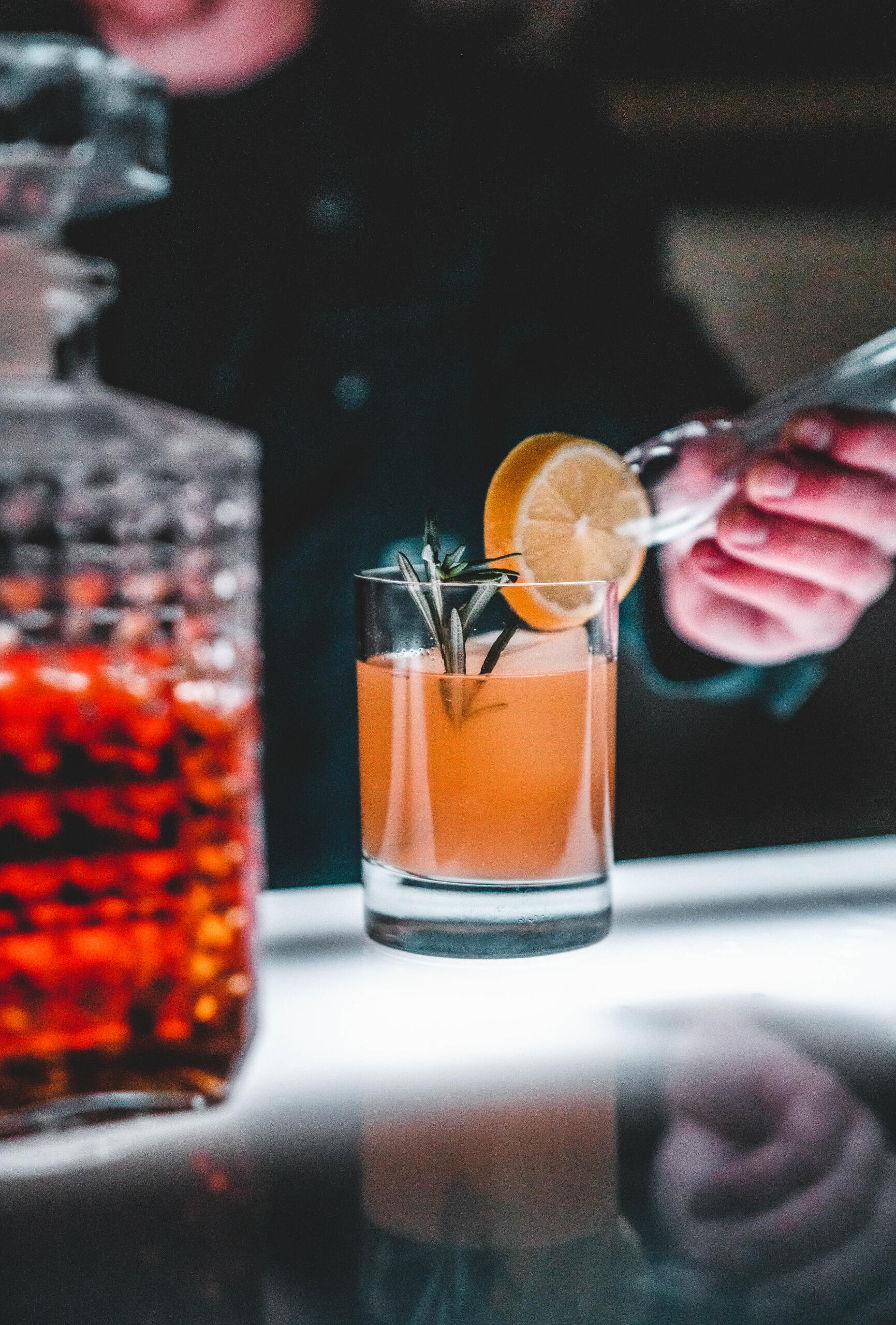 Craft Cocktail Service Bartender garnishing a craft cocktail beside a glass decanter.